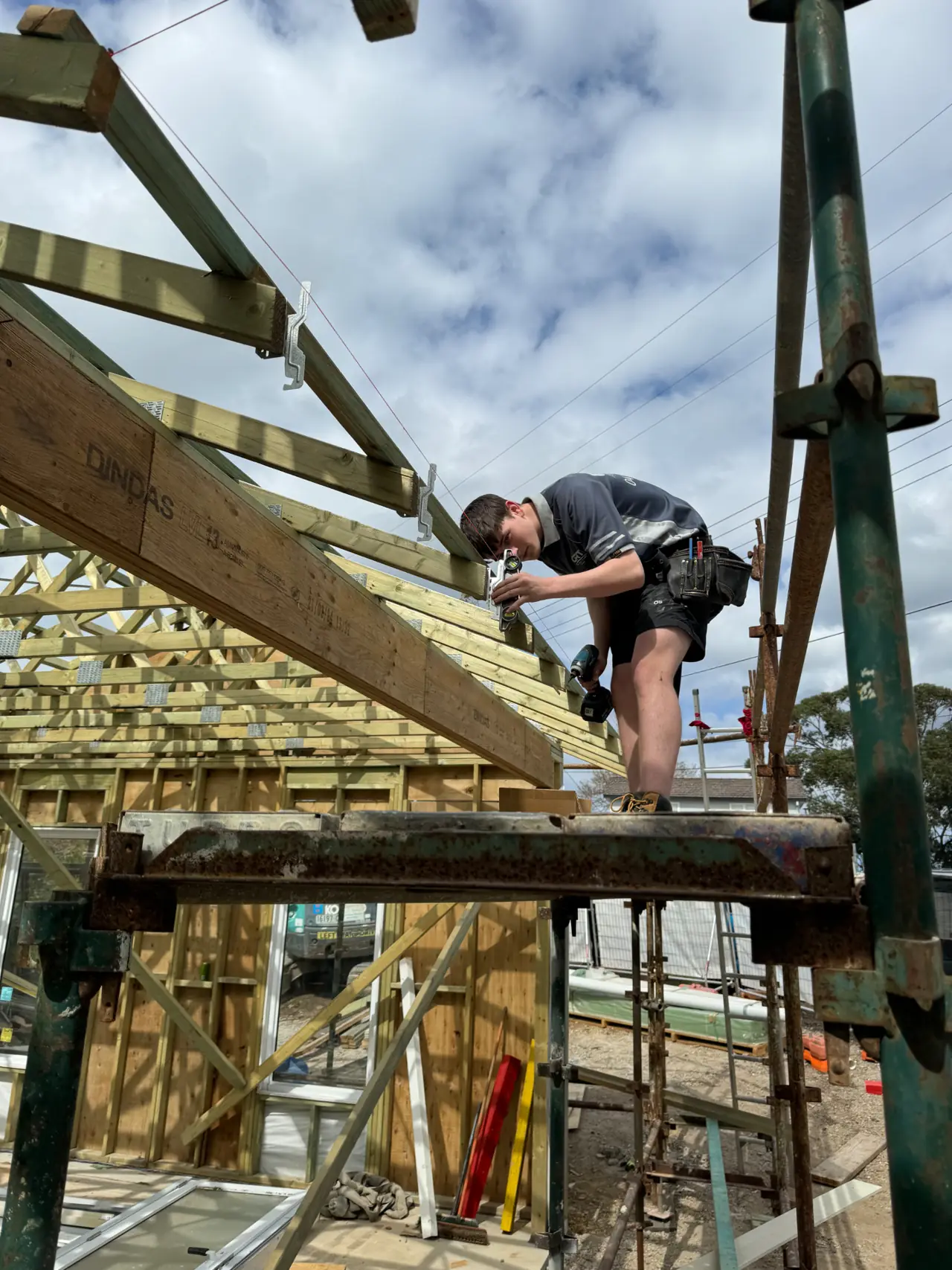 ORT carpenter working on timber roof framing beside scaffolding