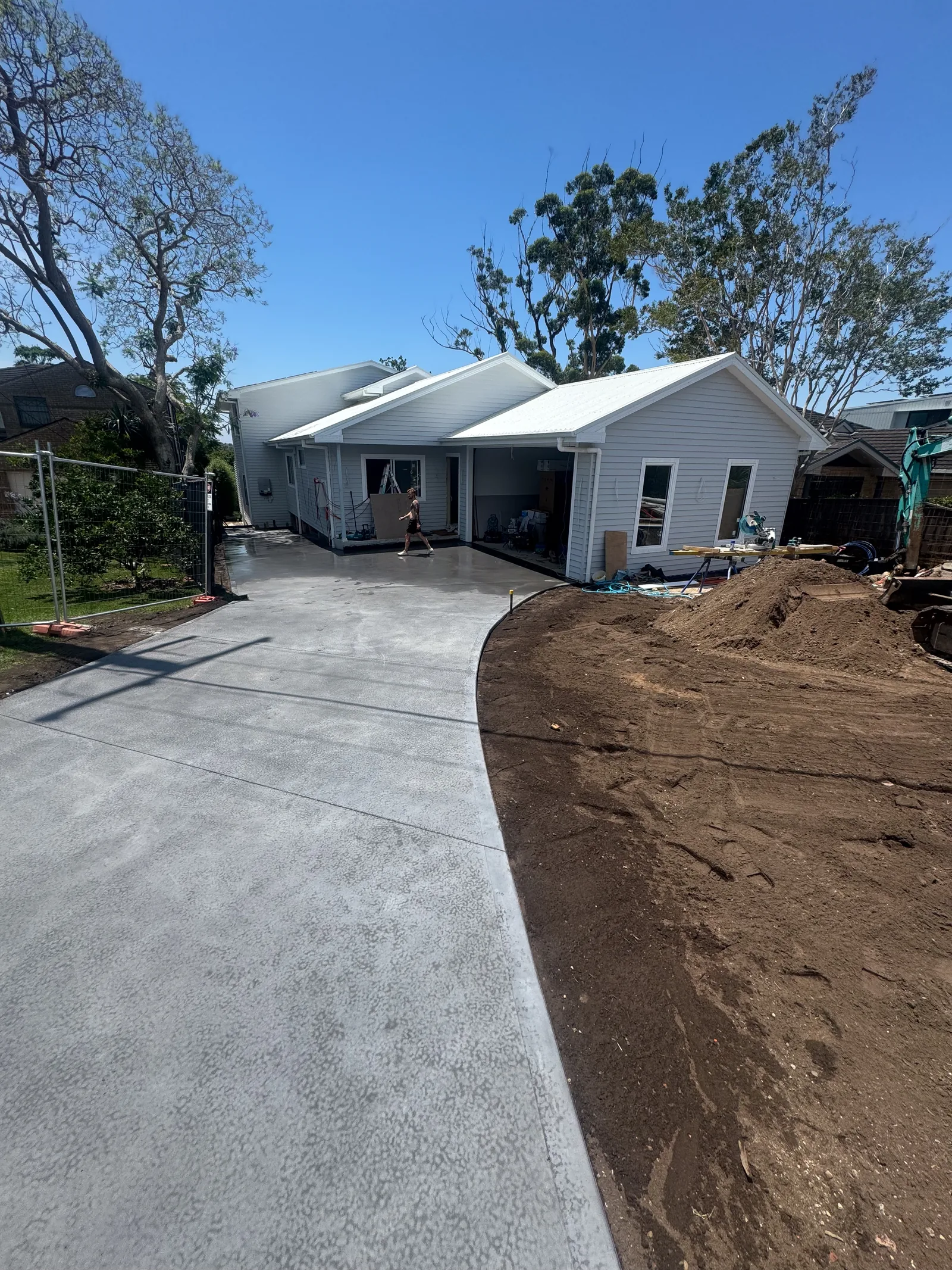 Wide concrete driveway poured to the front of a home with site fencing in place