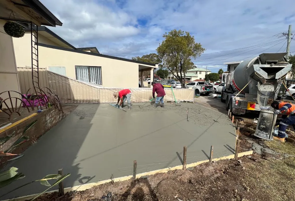 ORT Constructions team screeding a fresh concrete pour beside a house with the concrete truck on the street