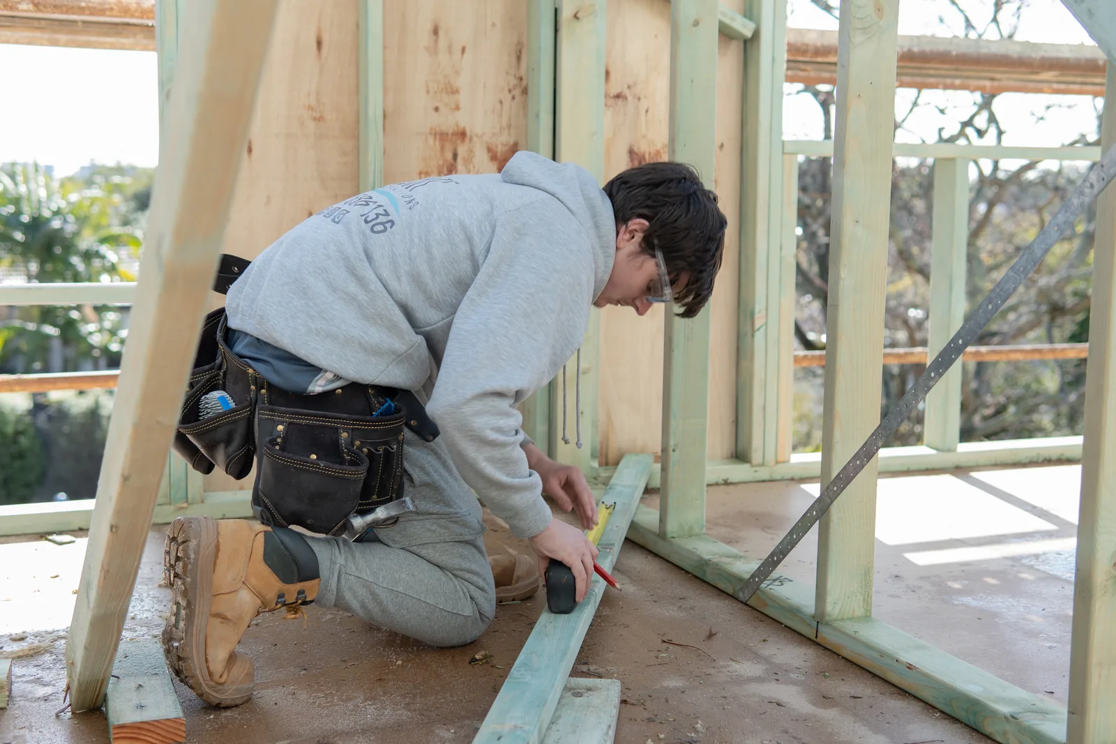 Carpenter fixing noggins into the timber wall frame of the rebuild