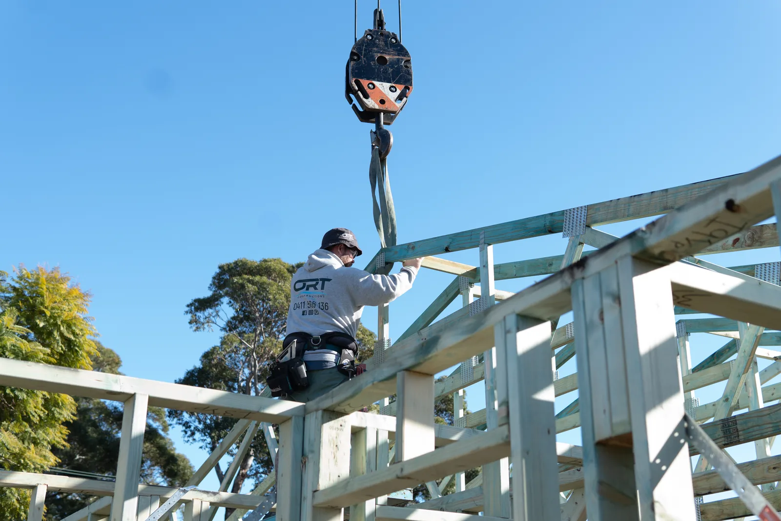 ORT Constructions carpenter guiding a roof truss into position on the frame