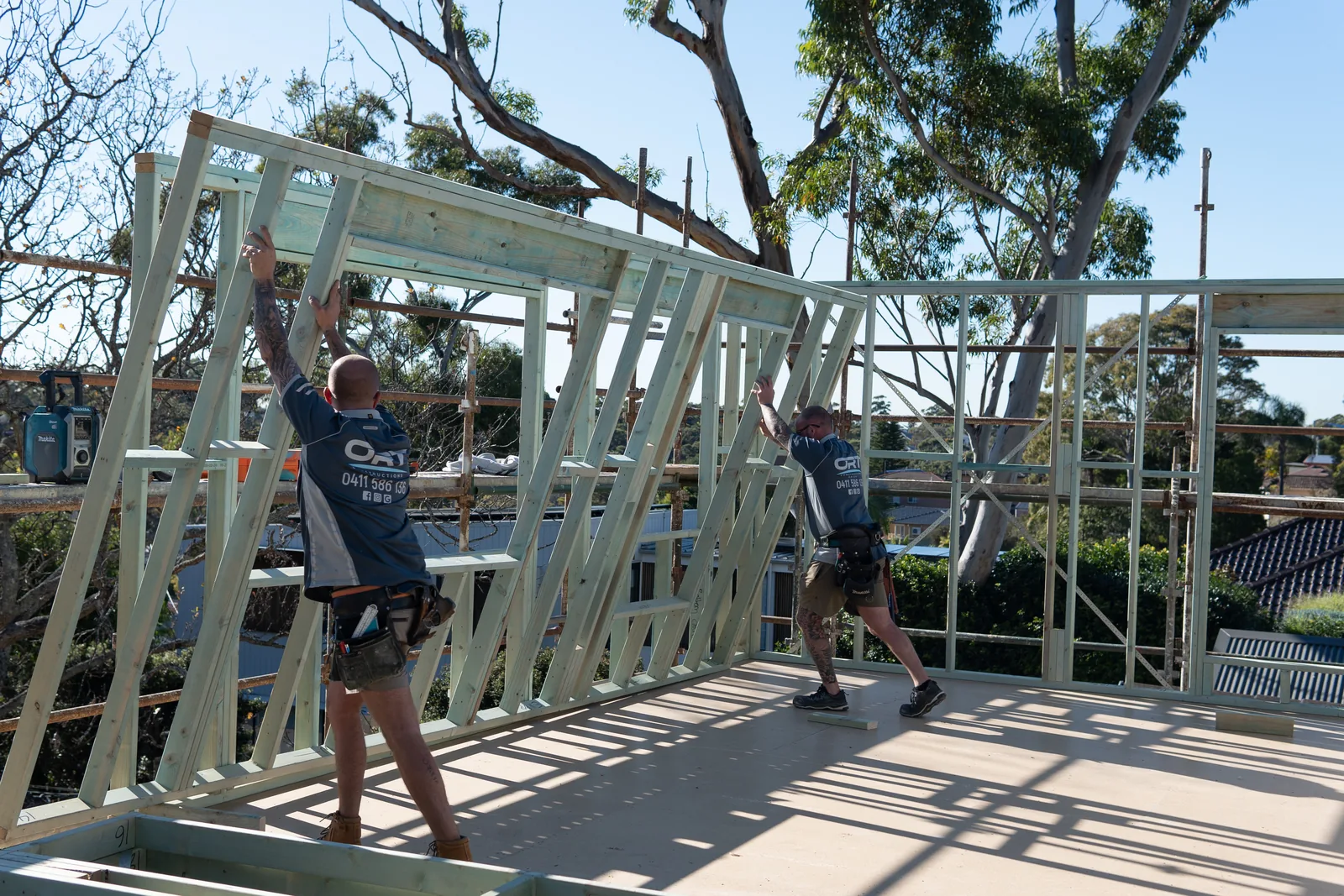 Two carpenters standing timber wall frames on the upper floor of the rebuild