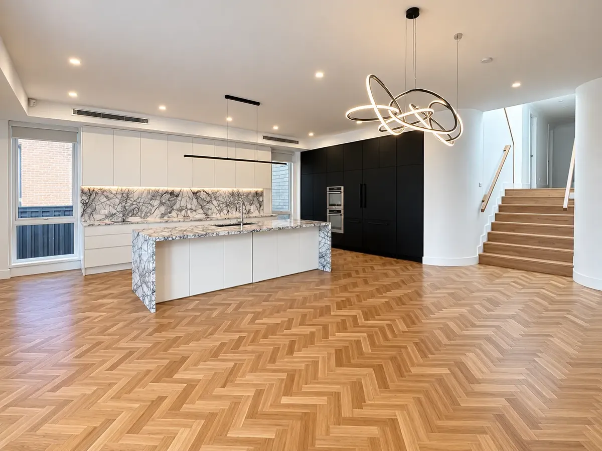 Modern kitchen and dining space with stone island bench and herringbone timber flooring at Gymea Bay