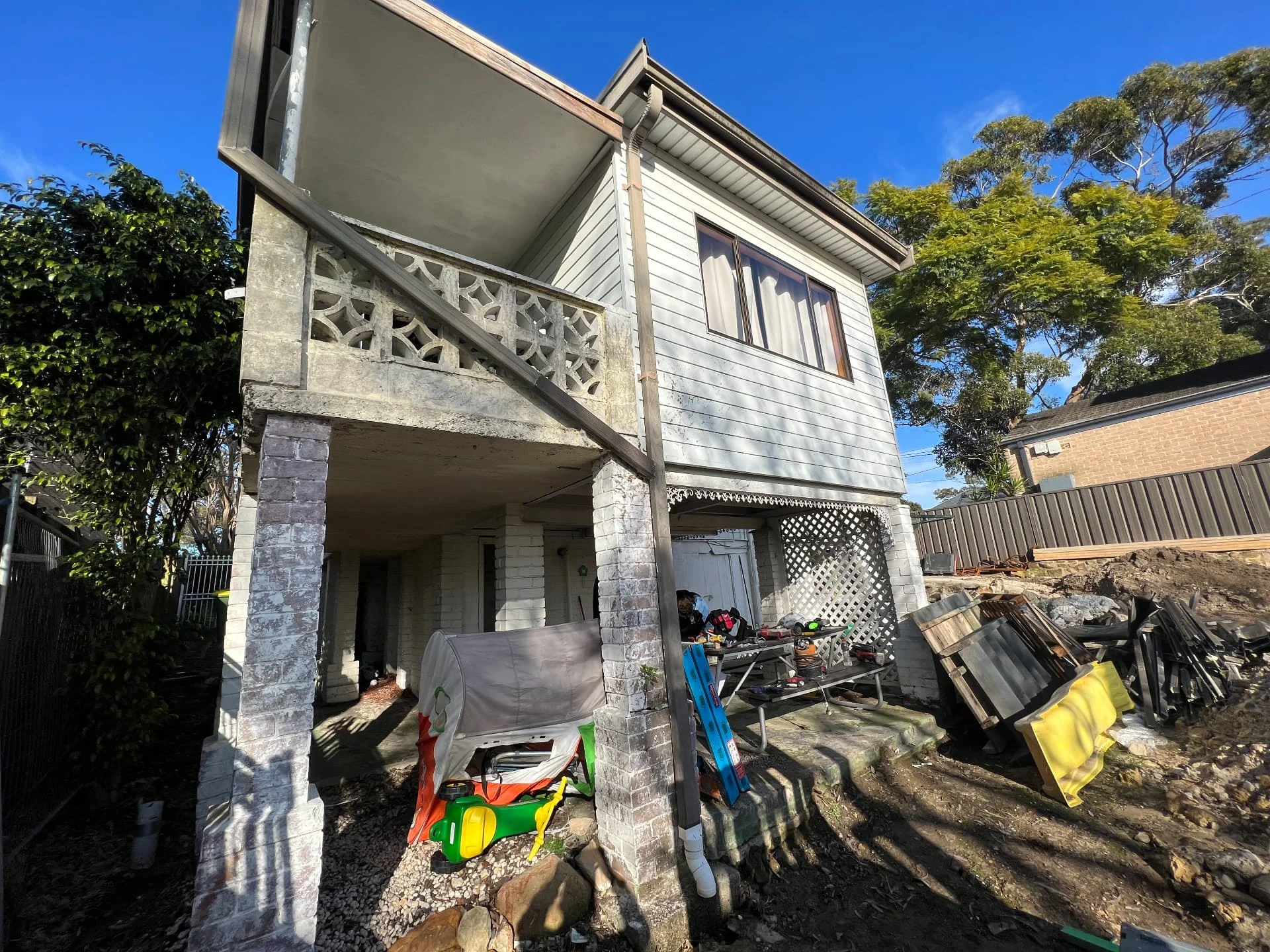 Rear of the original two storey home at Gymea Bay before the rebuild, with breeze block balustrade and excavated site