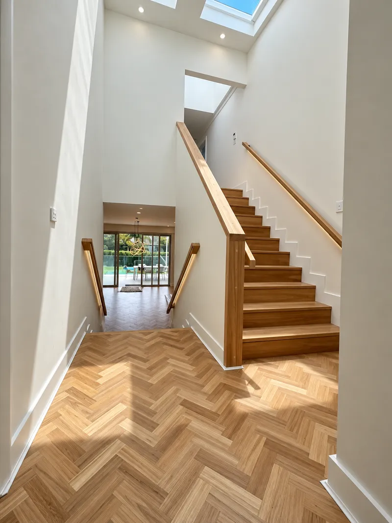 Timber staircase with LED handrails and herringbone flooring leading down to the open plan living area at Gymea Bay