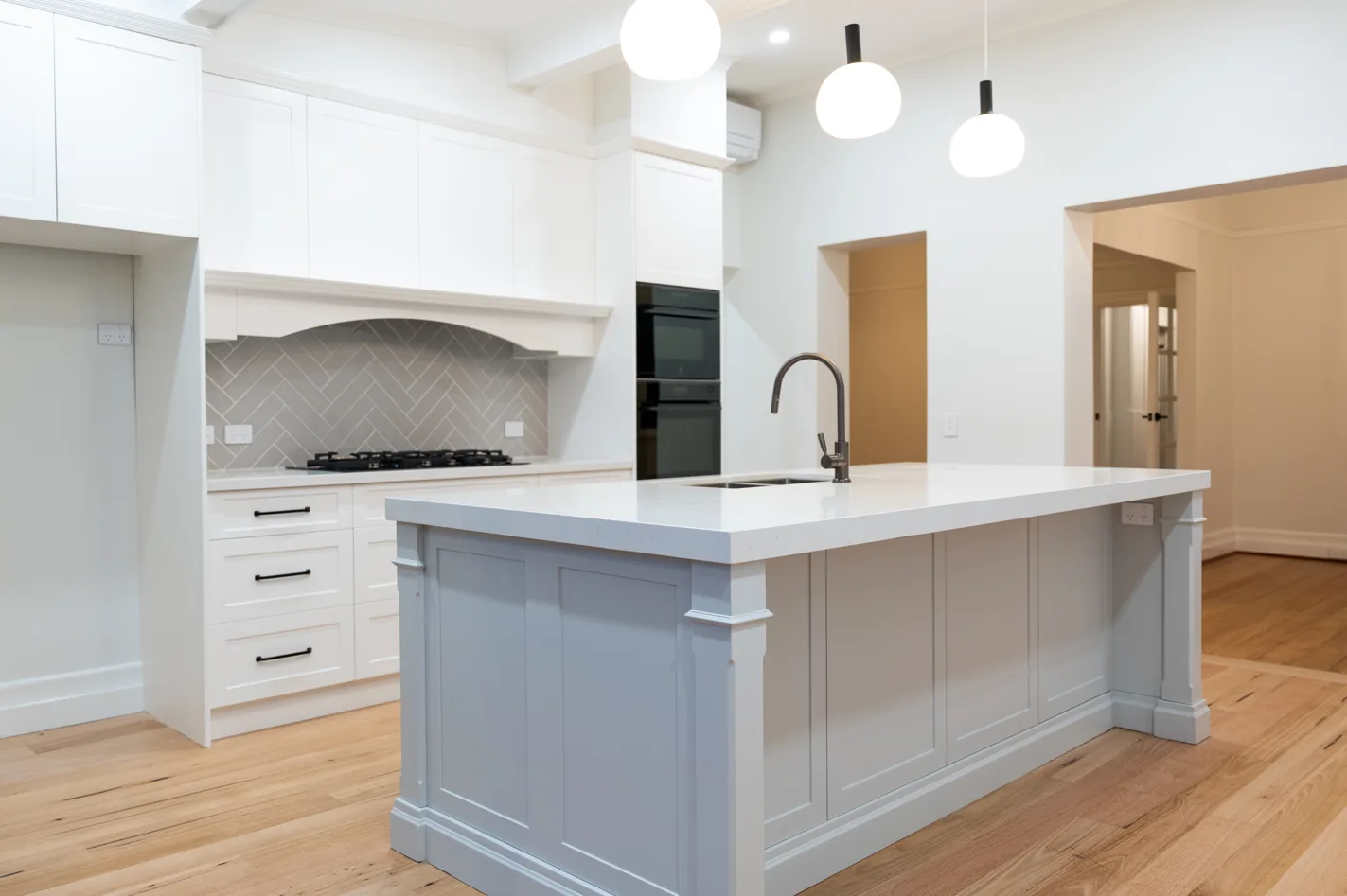 Renovated kitchen with shaker cabinetry, stone island bench and herringbone tiled splashback