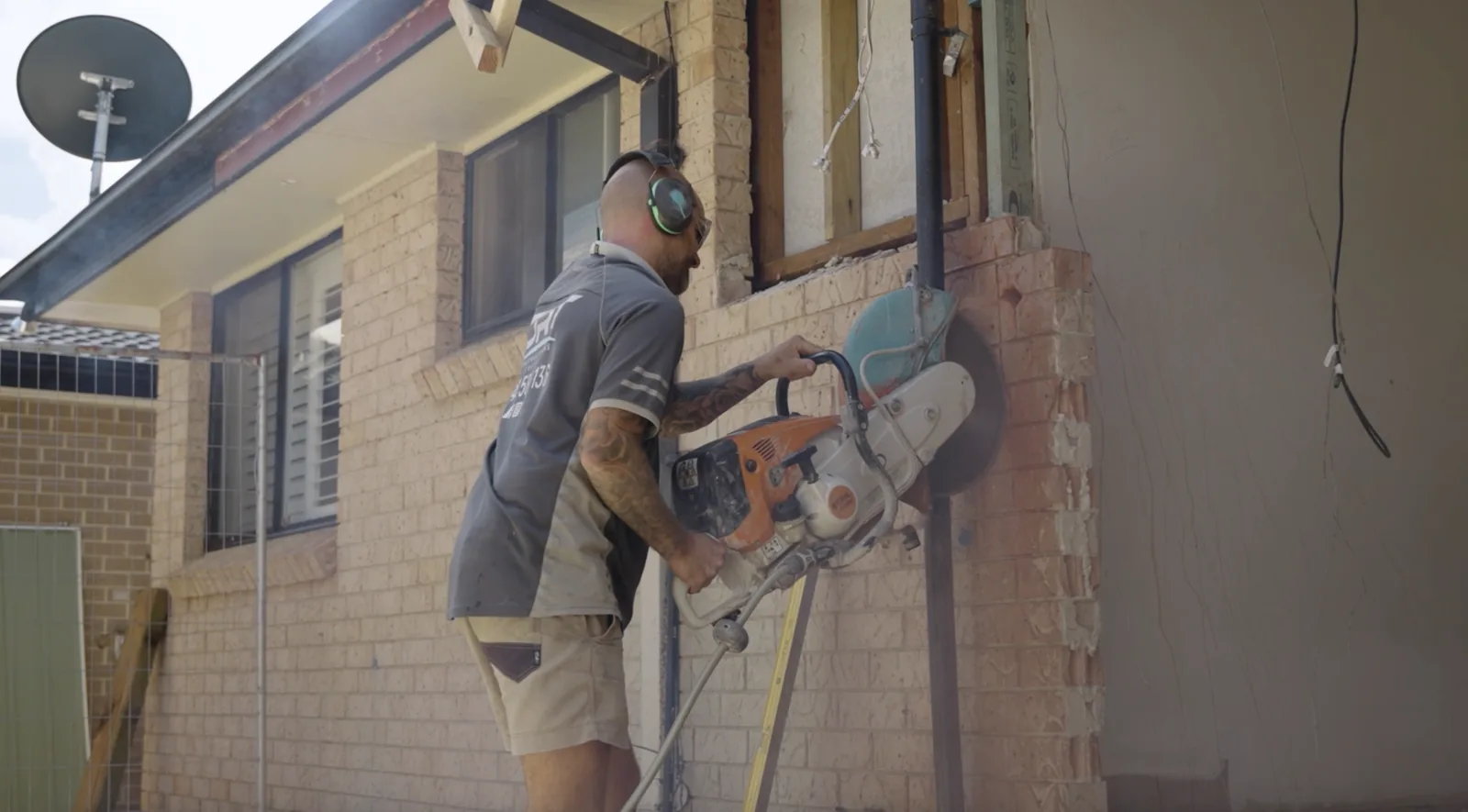 Tradesman cutting into an existing brick wall to form a new opening