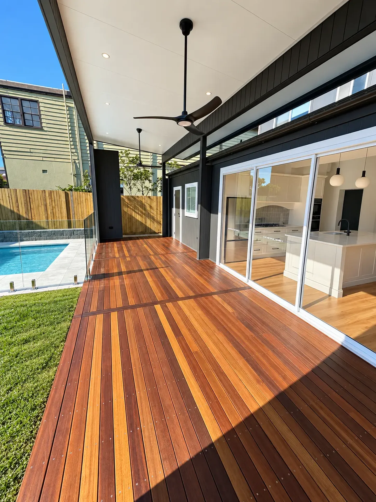 Covered hardwood alfresco deck with glass pool fencing and sliding doors to the kitchen at Russell Lea