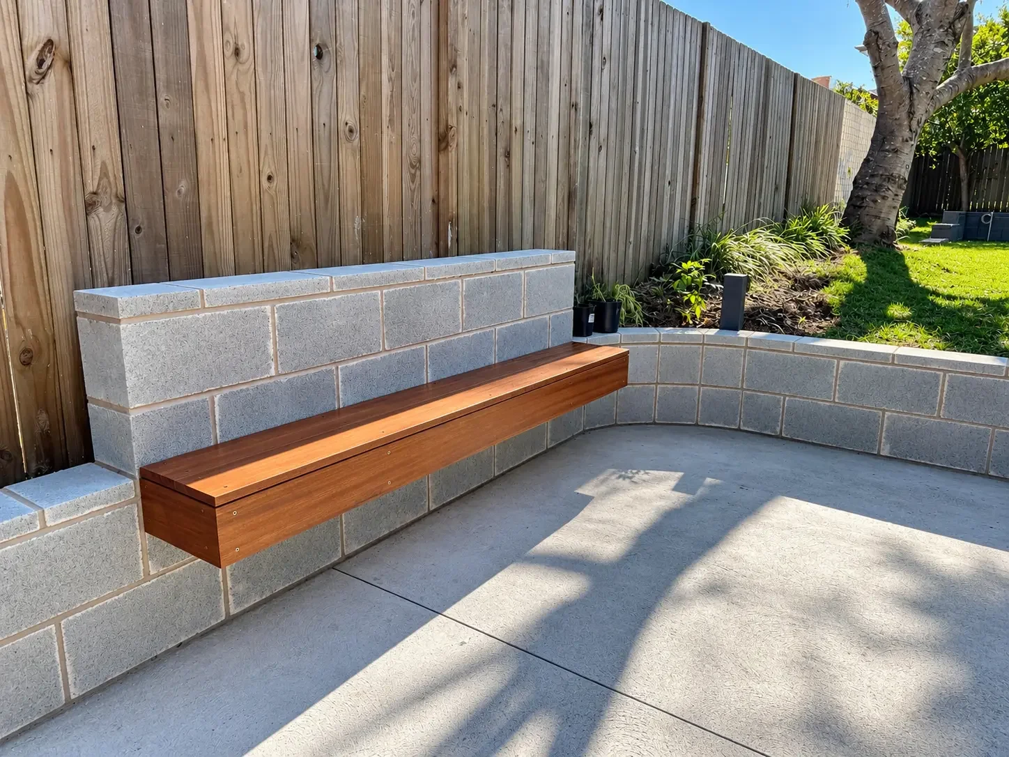 Floating timber bench seat built into a curved block retaining wall at Russell Lea