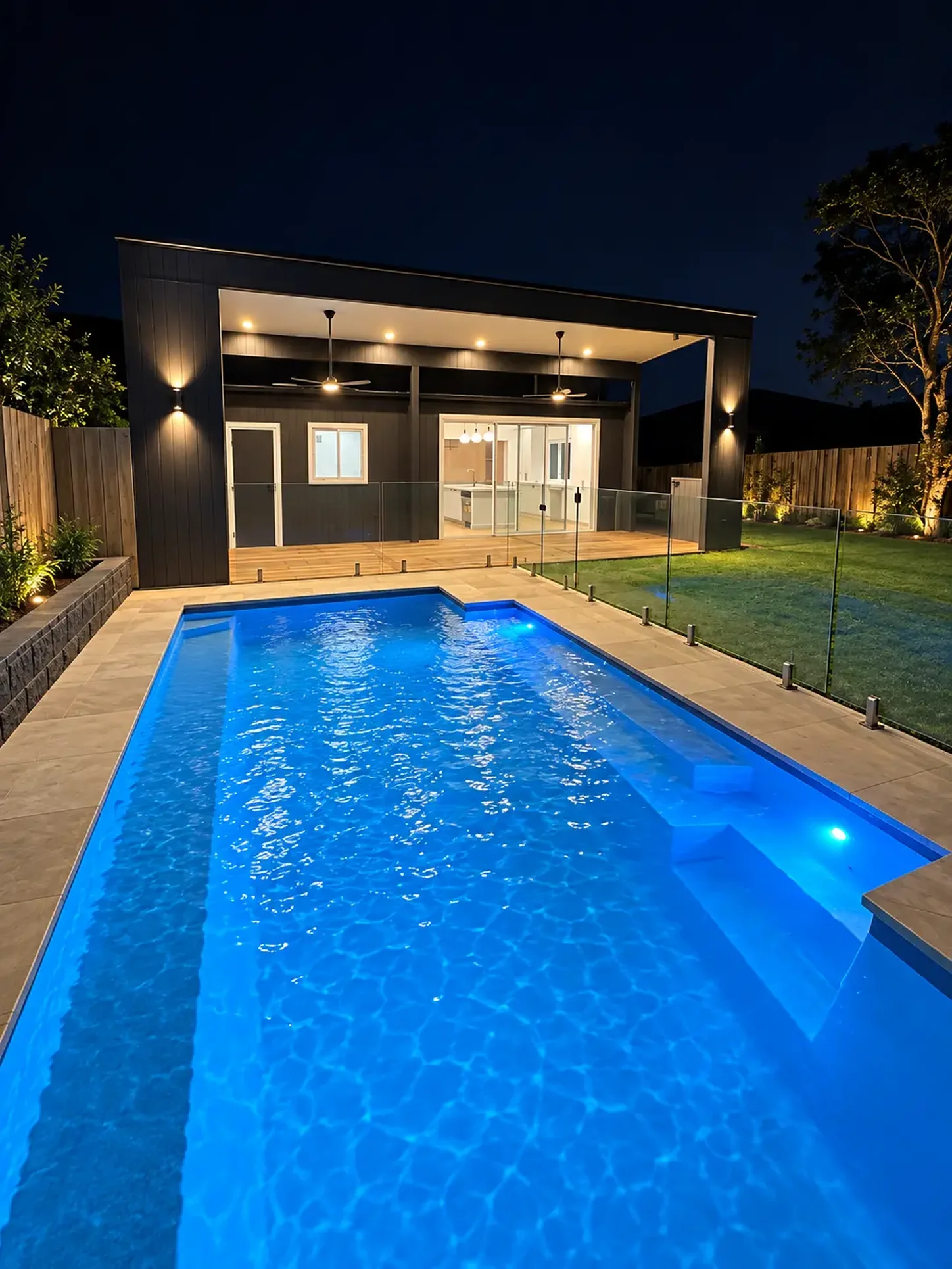Inground pool and dark clad alfresco area lit at night at Russell Lea