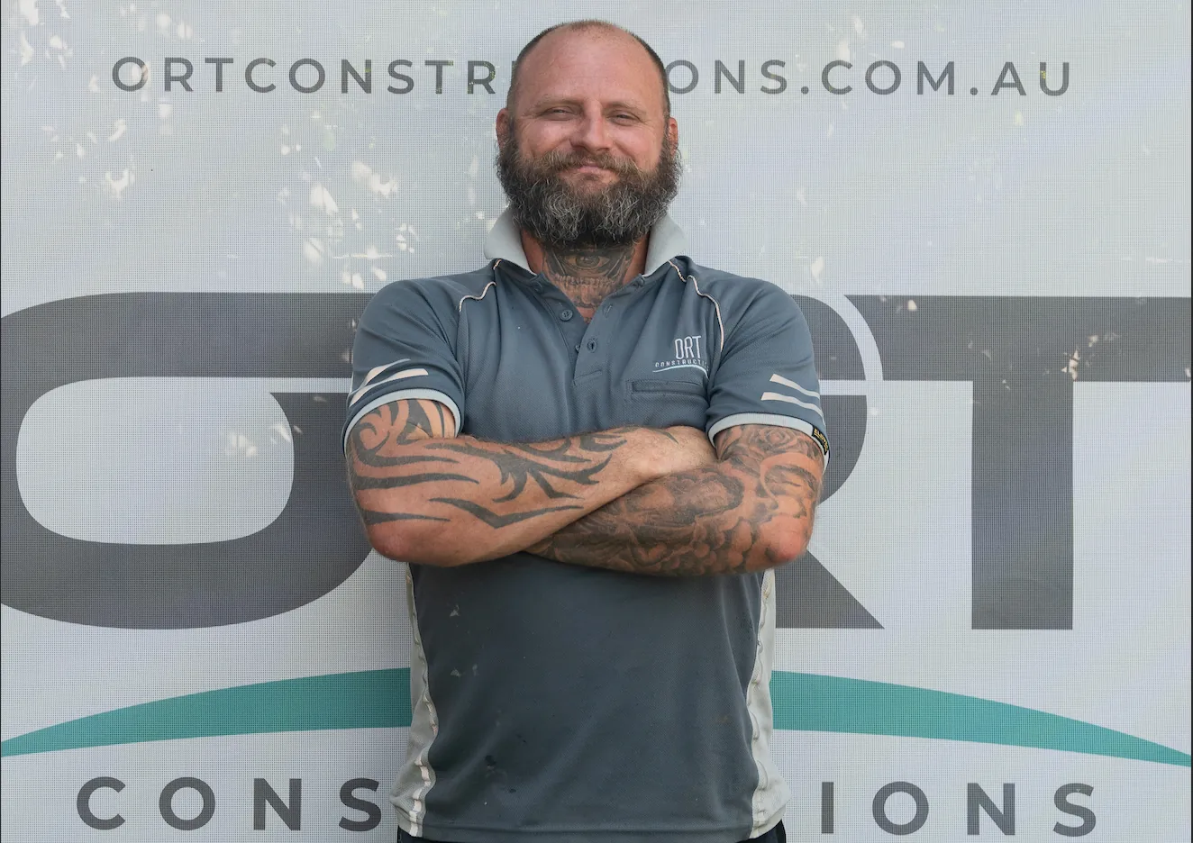 Jaxson, Leading Hand at ORT Constructions, in front of an ORT Constructions site banner
